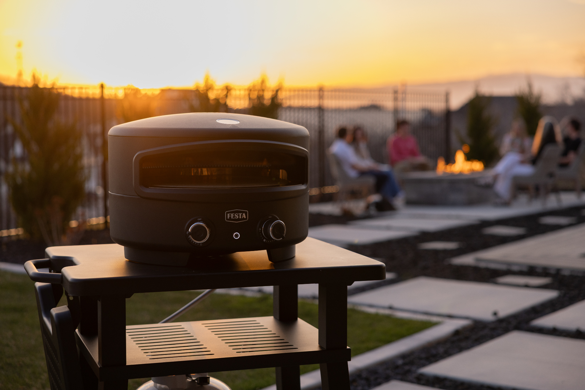 Festa oven on cart at sunset with friends gathered around a fire pit