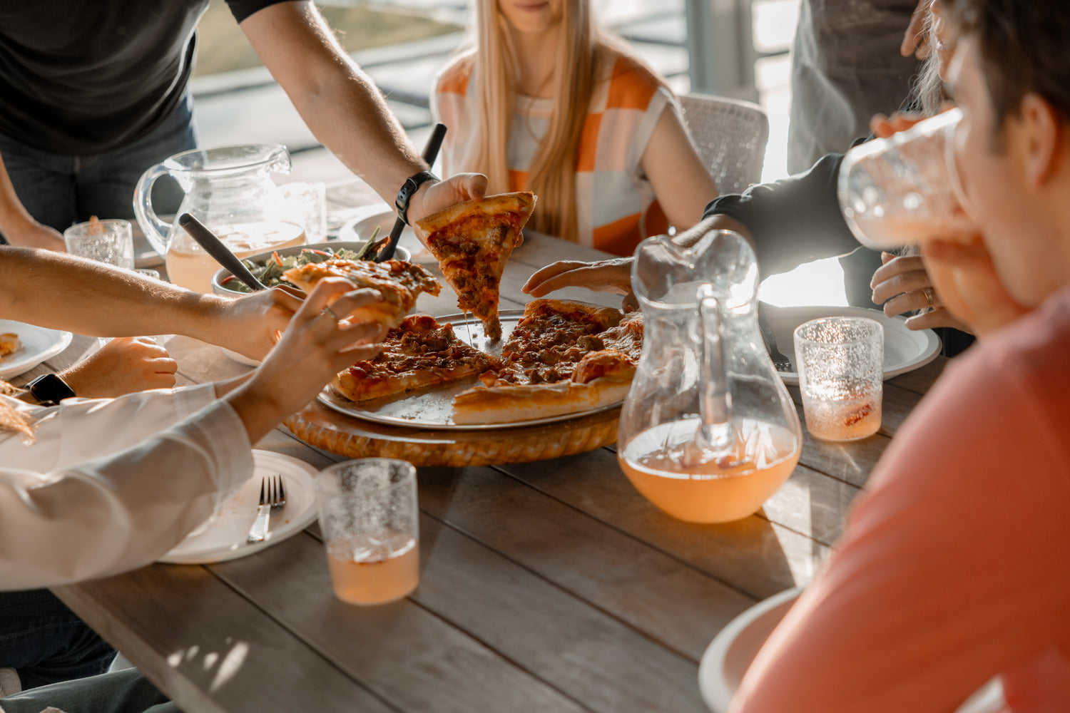 People gathered around a table eating pizza and drinking.